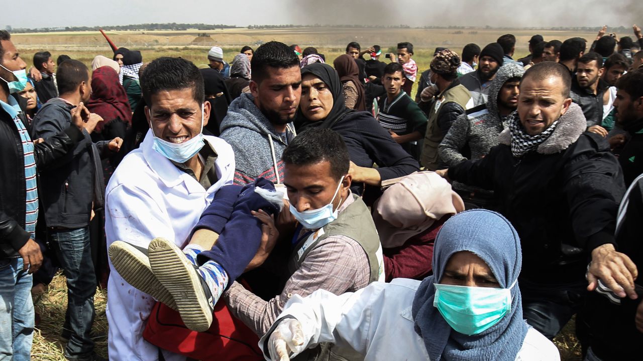 An injured Palestinian woman is carried by protesters as they run for cover during clashes with Israeli security forces on March 30, 2018.