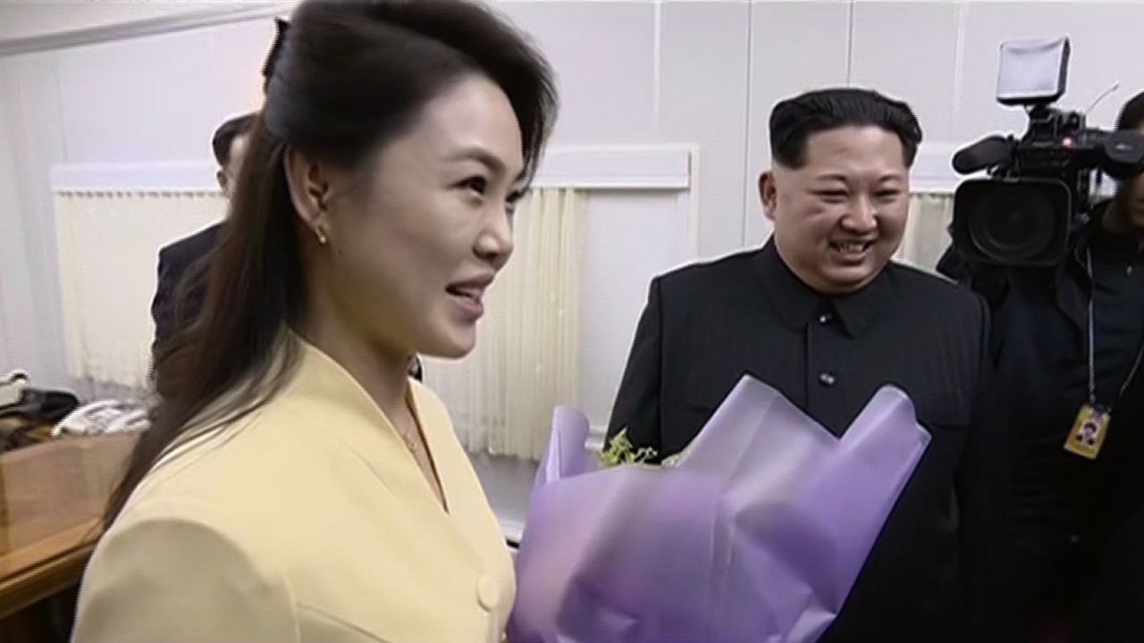 Kim's wife Ri Sol Ju is shown holding a bouquet of flowers given to her husband on their arrival in Dandong.