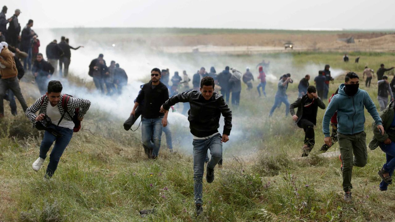 Palestinian protesters flee tear gas during clashes with Israeli forces at the Gaza border on Friday. 