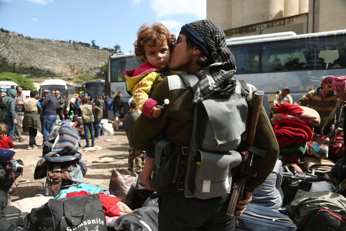 A rebel fighter from Eastern Ghouta kisses a child after arriving last week in Qalaat al-Madiq, Syria. 