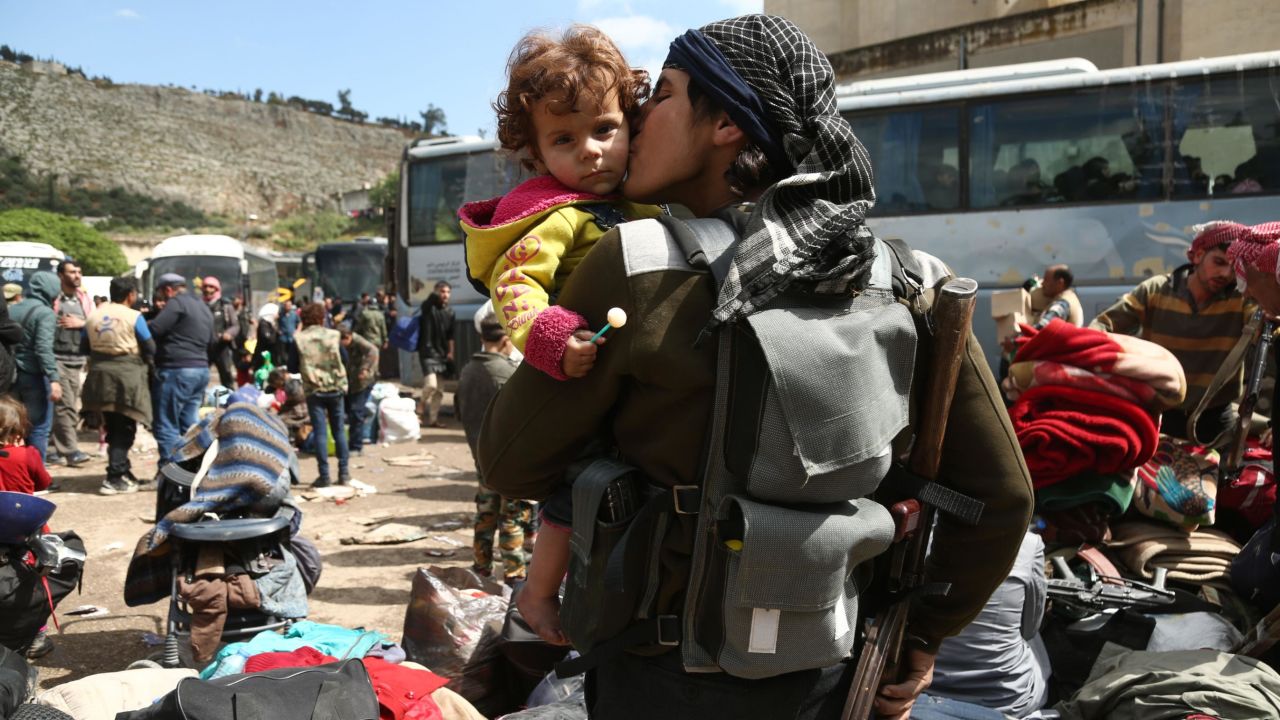 A rebel fighter from Eastern Ghouta kisses a child after arriving in Qalaat al-Madiq on Friday, as part of the ongoing evacuation deals. 