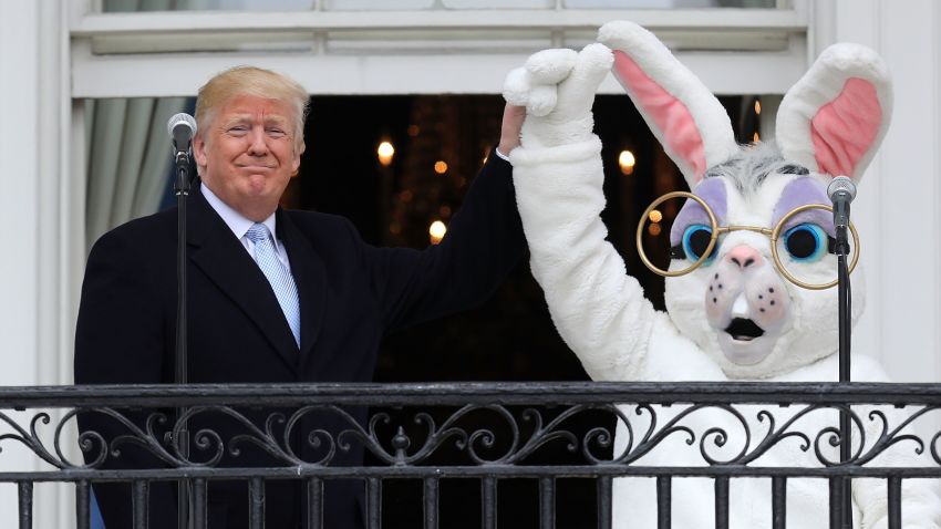 U.S. President Donald Trump (L) lifts the hand of a person in an Easter Bunny costume on the Truman Balcony during the 140th annual Easter Egg Roll on the South Lawn of the White House April 2, 2018 in Washington, DC. The White House said they are expecting 30,000 children and adults to participate in the annual tradition of rolling colored eggs down the White House lawn that was started by President Rutherford B. Hayes in 1878.  (Photo by Chip Somodevilla/Getty Images)