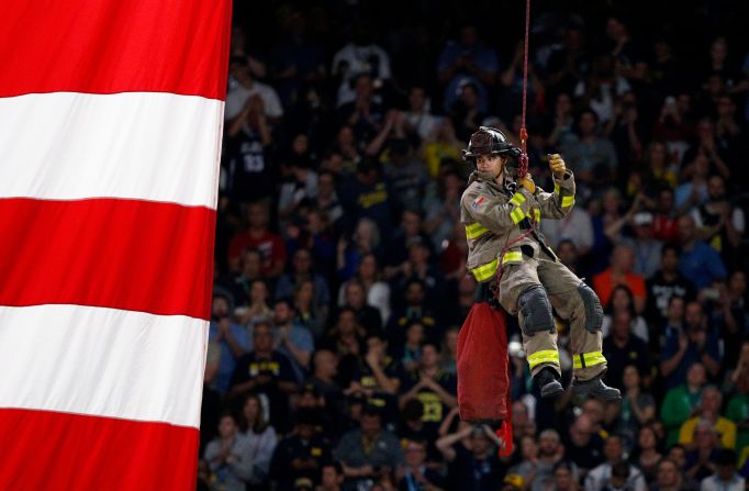 A firefighter repels to the court during the National Anthem.