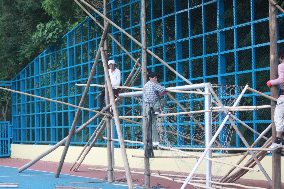 Workers begin building the back of the theater. They are anchoring wooden poles to the soccer goal.