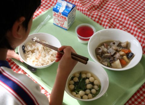 A school girl eats lunch, consisting of rice and stew, at Senzoku Elementary School in Tokyo, Japan. In Japan, many students serve each other lunch and enjoy their meals in relaxed environments in the classroom.