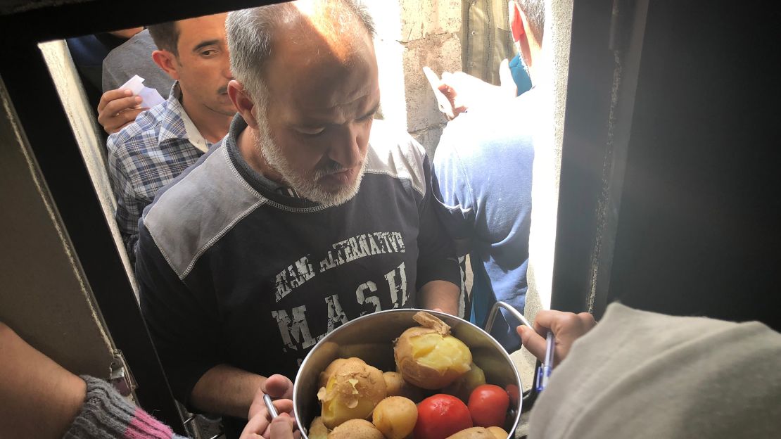 A man picks up his food handout after waiting in a long line in scorching heat. 