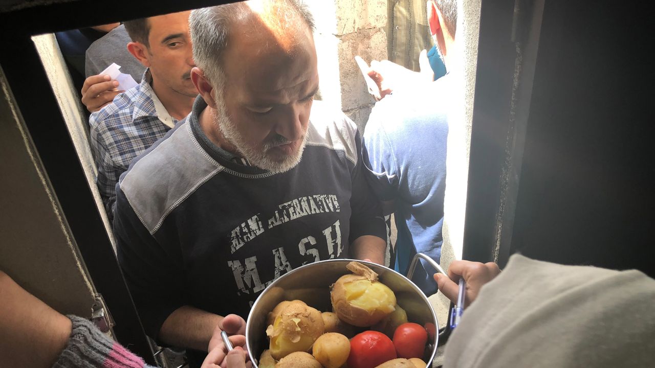 A man picks up his food handout after waiting in a long line in scorching heat.