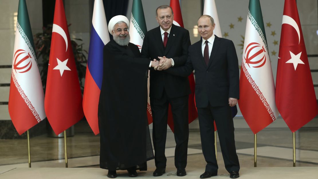 Iran's President Hassan Rouhani, Turkey's President Recep Tayyip Erdogan and Russia's President Vladimir Putin lock hands during a group photo in Ankara on Wednesday.