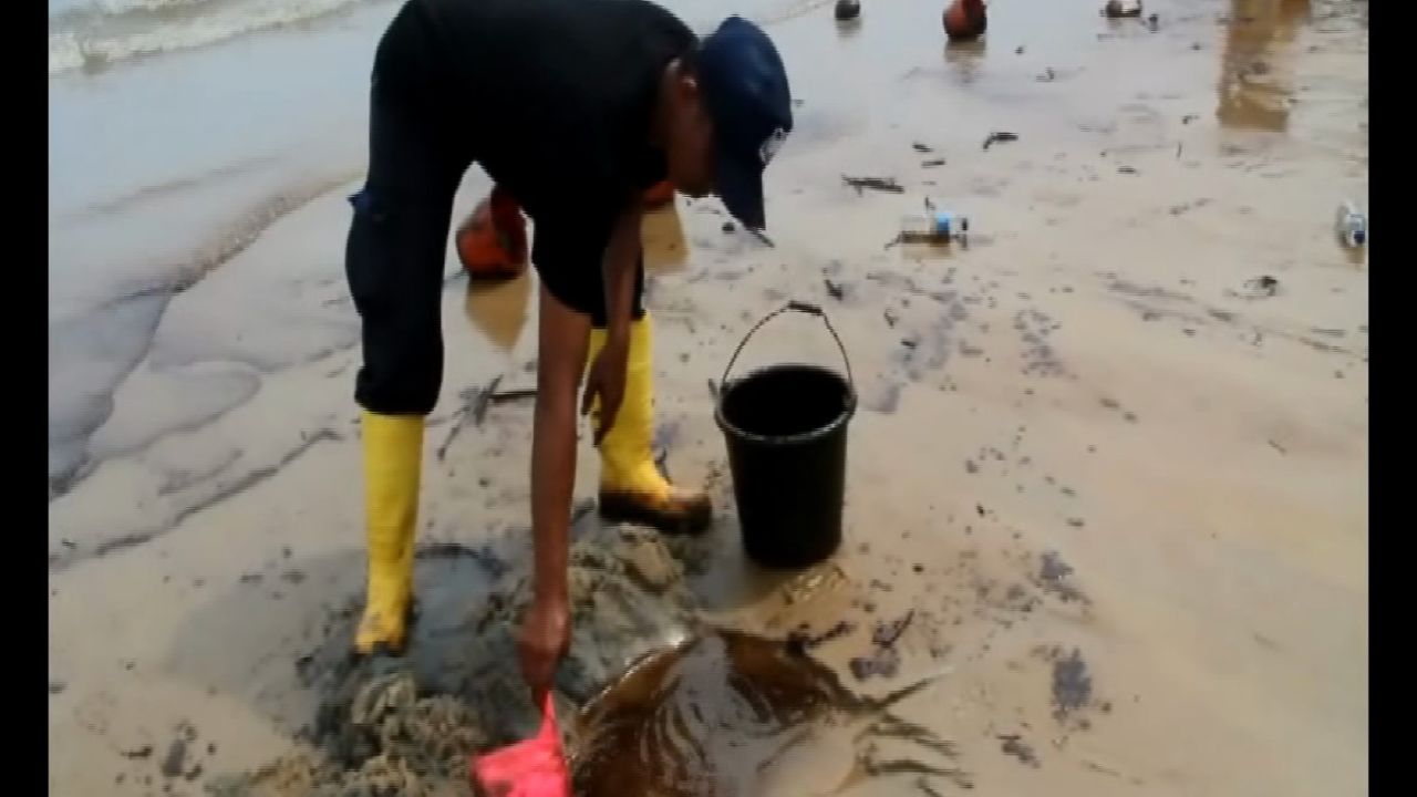 A worker collects oil from a beach following a spill in Balikpapan, East Kalimantan, Indonesia in this screengrab from CNN affiliate CNN Indonesia. 
