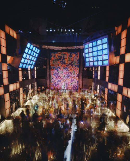 As clubs merged art and nightlife, figures like Keith Haring collaborated with venues to create fliers, posters and interiors. Here, dancers are pictured beneath an enormous Haring mural at New York's Palladium in the mid-1980s.