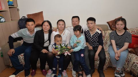 The families of Wang Mingqing and his missing daughter Kang Ying, second left, pose for photos after reuniting.