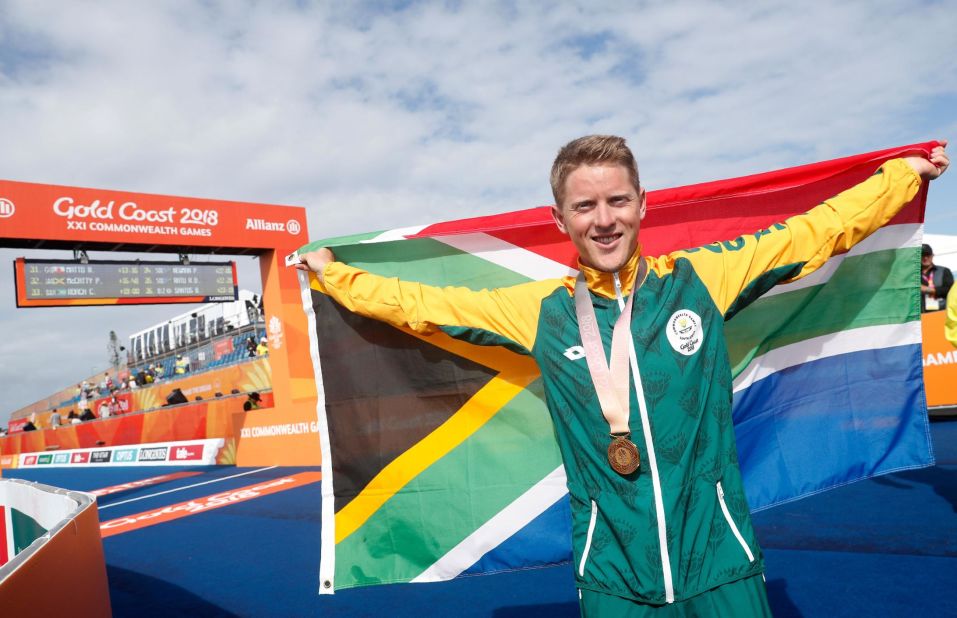 South Africa's Henri Schoeman poses with his country's flag after winning the men's triathlon final.