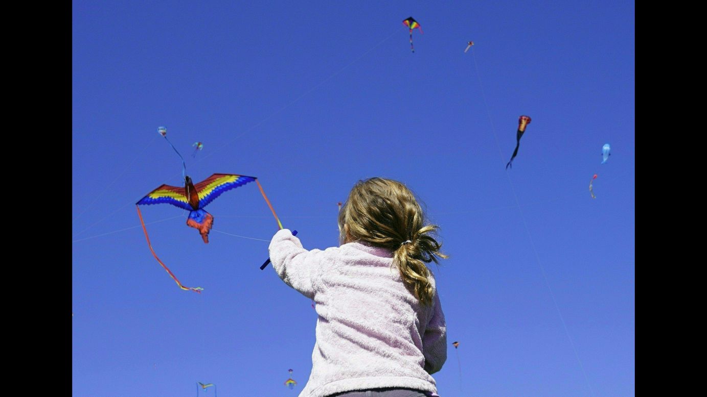 A girl sitting on her father's shoulders tries to control her kite as she takes part in the annual Blossom Kite Festival in Washington on Saturday, March 31.