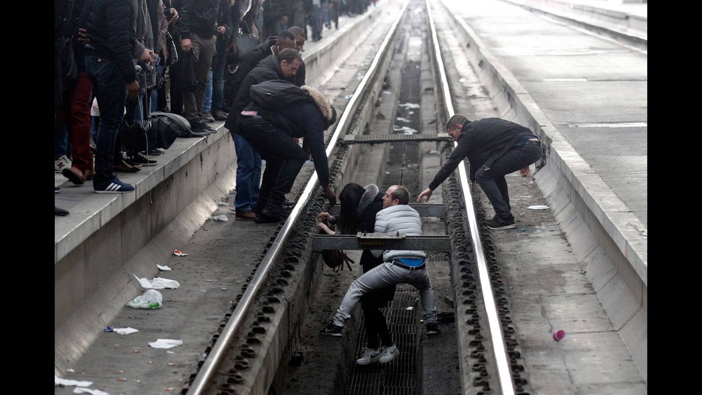 Passengers assist a woman who fell off a platform as she was trying to cross railroad tracks in Paris on Tuesday, April 3. Rail workers across France <a href="https://www.cnn.com/2018/04/03/europe/france-rail-strikes-intl/index.html" target="_blank">have gone on strike this week,</a> severely disrupting train services.