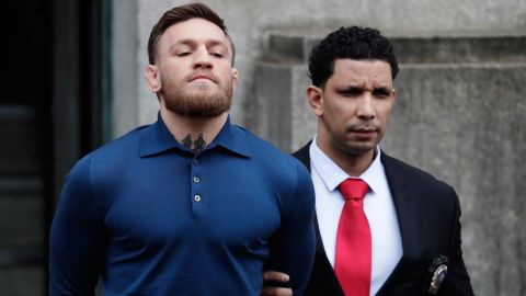 Conor McGregor, left, is led to a vehicle while leaving an NYPD building Friday morning. 
