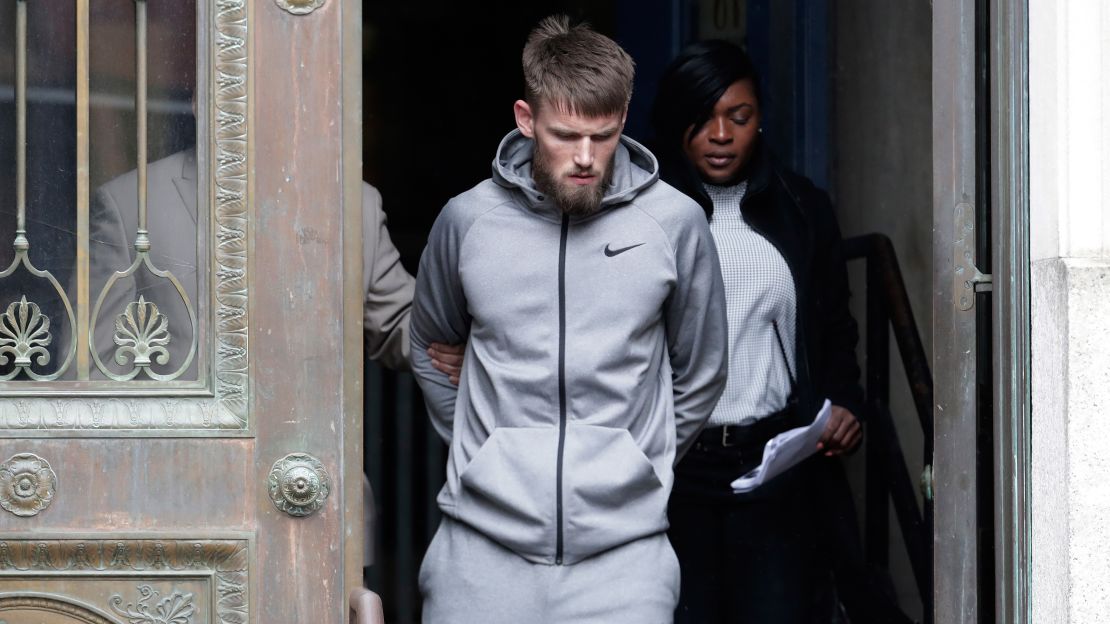 Mixed martial arts fighter Cian Cowley is led Friday morning from the NYPD's 78th precinct building.