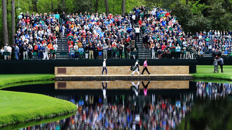 Patrick Reed of the United States, Rory McIlroy of Northern Ireland and caddie Kessler Karain cross the Sarazen Bridge on the 16th hole.