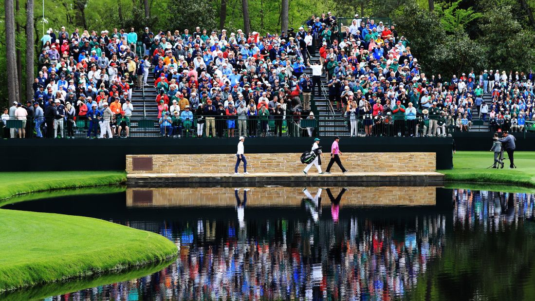 Patrick Reed of the United States, Rory McIlroy of Northern Ireland and caddie Kessler Karain cross the Sarazen Bridge on the 16th hole.