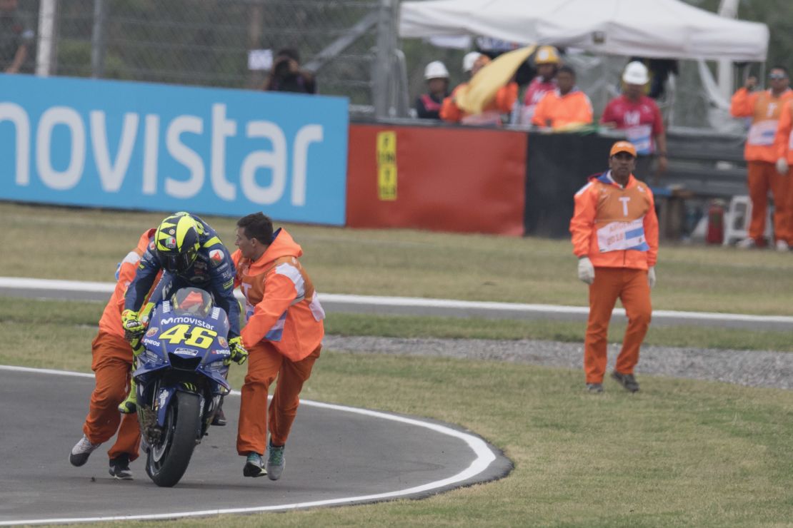 Valentino Rossi is helped back onto his bike after crashing out.