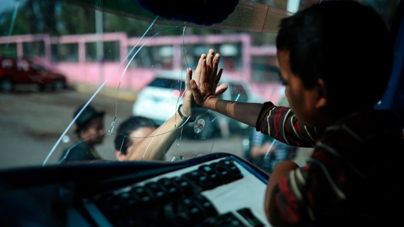 A boy says goodbye to a friend through the windshield of a bus in Matias Romero, Mexico, on Thursday, April 5. Central American migrants taking part in an annual caravan were boarding buses to Mexico City and the nearby city of Puebla. The caravan's primary goal is to "flee Central America" and seek asylum within Mexico or the United States, according to Alex Mensing, who works for the group that organizes the caravan. <a href="https://www.cnn.com/2018/04/01/politics/trump-mexico-caravan-tweet/index.html" target="_blank">This year's journey</a> is getting more attention than usual after a series of tweets from US President Donald Trump.