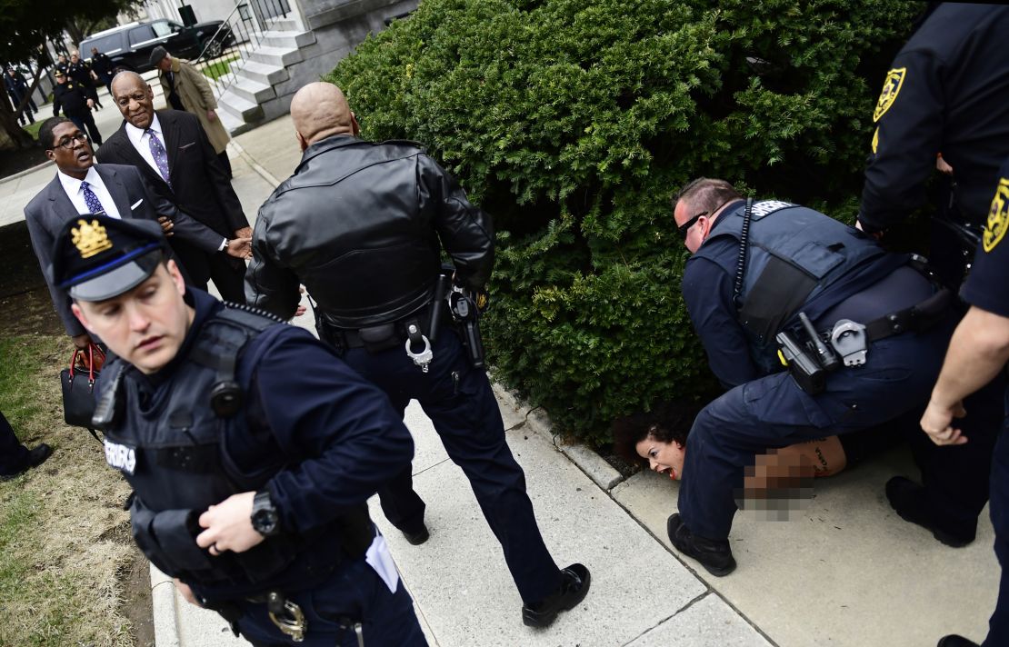 A protester is detained after Bill Cosby arrives for his sexual assault trial.