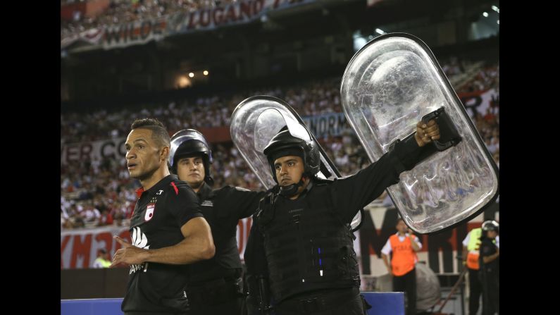 Police hold up shields near Anderson Plata, protecting the Santa Fe player from possible projectiles, as he takes a corner kick against River Plate on Thursday, April 5. The match in Buenos Aires ended scoreless.