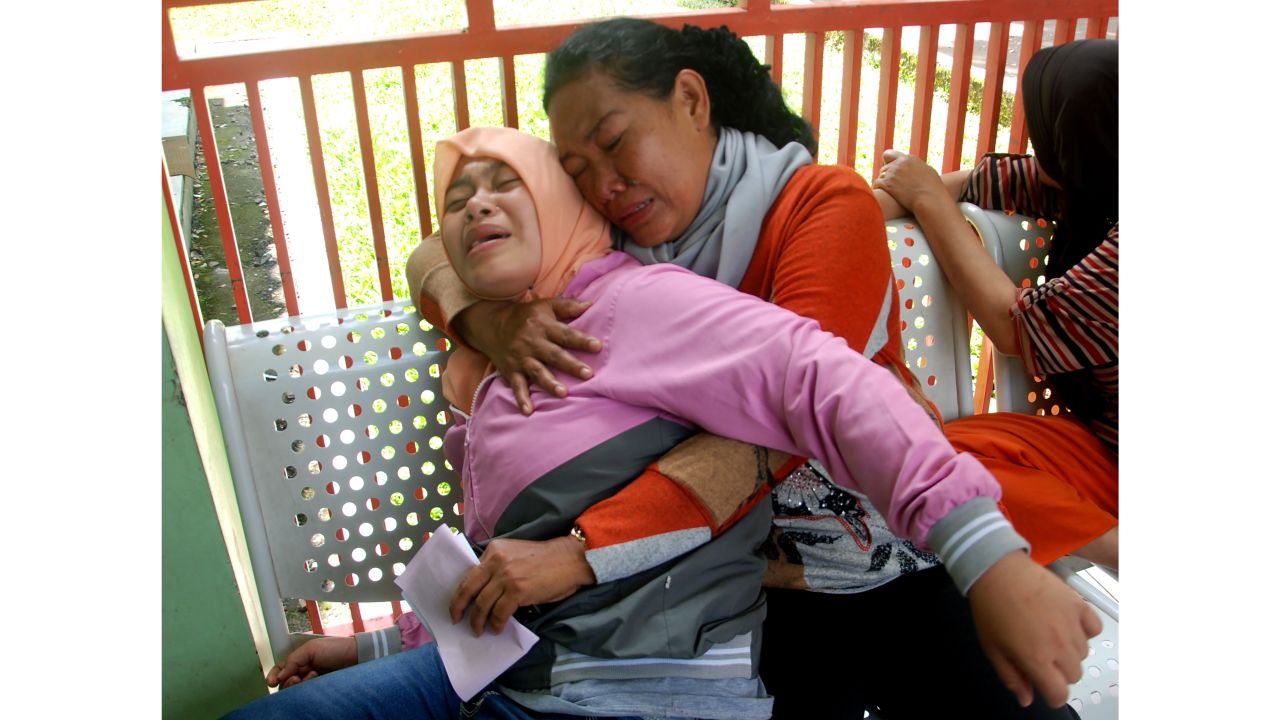 Two Indonesian women react after hearing that a family member died from drinking illegal alcohol.