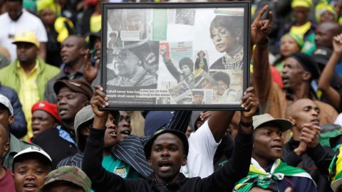 A man holds up a frame showing newspaper clippings of Madikizela-Mandela.