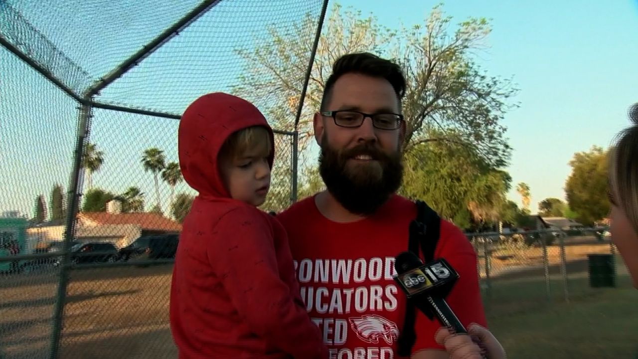 Justin McLellan holds one of his children at Wednesday's rally.