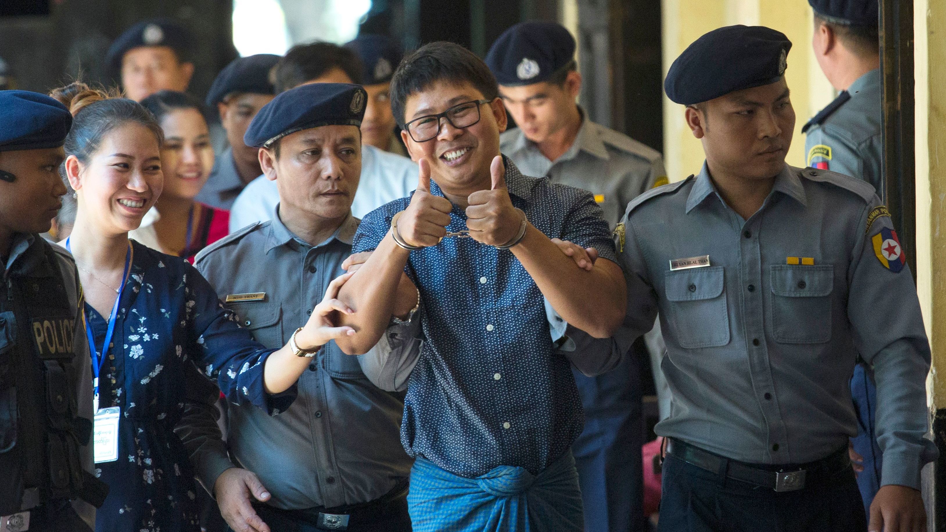 Detained Myanmar journalist Wa Lone, center, gives a thumbs up to reporters as he is escorted by police to a court for his ongoing trial in Yangon on April 11, 2018.

