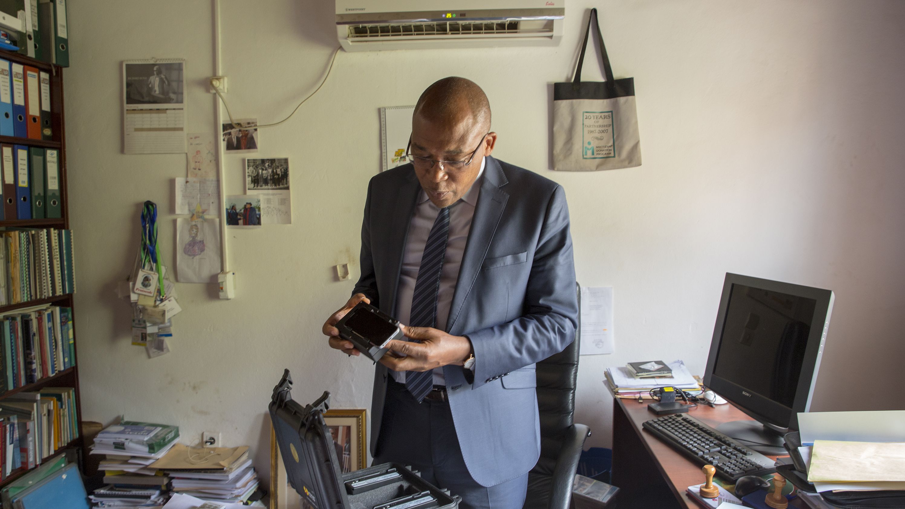 Dr. Joseph Kamgno examines a new version of a cellphone-based microscope in his research facility in Yaoundé, Cameroon.
