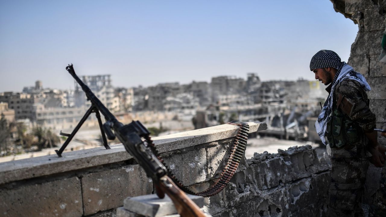 A fighter of the Syrian Democratic Forces (SDF) stands guard on a rooftop in Raqa on October 20, 2017, after retaking the city from Islamic State (IS) group fighters.
SDF fighters flushed jihadist holdouts from Raqa's main hospital and municipal stadium, wrapping up a more than four-month offensive against what used to be the inner sanctum of IS's self-proclaimed "caliphate", which for three years saw some of the group's worst abuses and grew into a centre for both its potent propaganda machine and its unprecedented experiment in jihadist statehood. / AFP PHOTO / BULENT KILIC        (Photo credit should read BULENT KILIC/AFP/Getty Images)