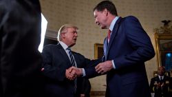 WASHINGTON, DC - JANUARY 22: U.S. President Donald Trump (C) shakes hands with James Comey, director of the Federal Bureau of Investigation (FBI), during an Inaugural Law Enforcement Officers and First Responders Reception in the Blue Room of the White House on January 22, 2017 in Washington, DC. Trump today mocked protesters who gathered for large demonstrations across the U.S. and the world on Saturday to signal discontent with his leadership, but later offered a more conciliatory tone, saying he recognized such marches as a "hallmark of our democracy." (Photo by Andrew Harrer/Pool/Getty Images)