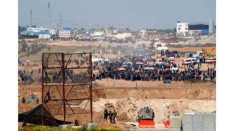 Israeli soldiers stand as Palestinian protesters gather along the Gaza-Israel border fence on Friday.