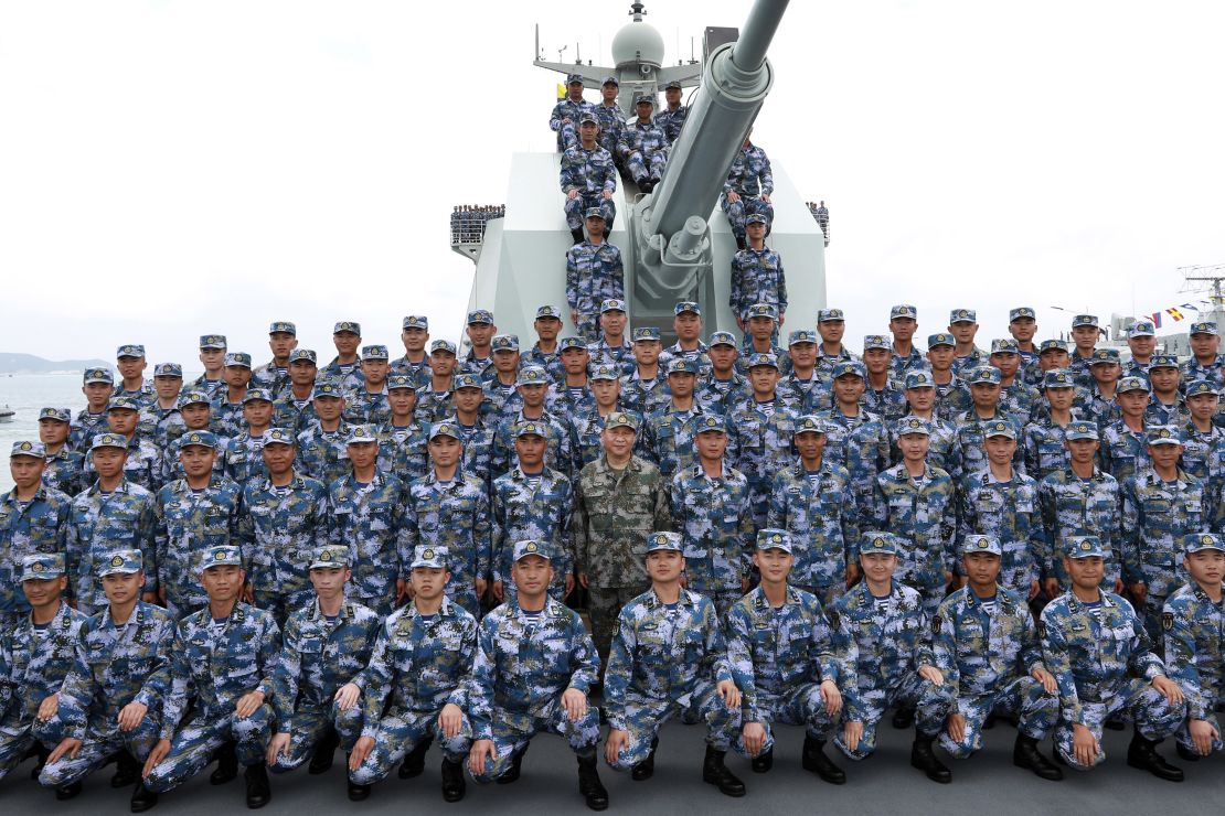 Chinese President Xi Jinping, center in green military uniform, poses with soldiers on a navy ship on April 12.