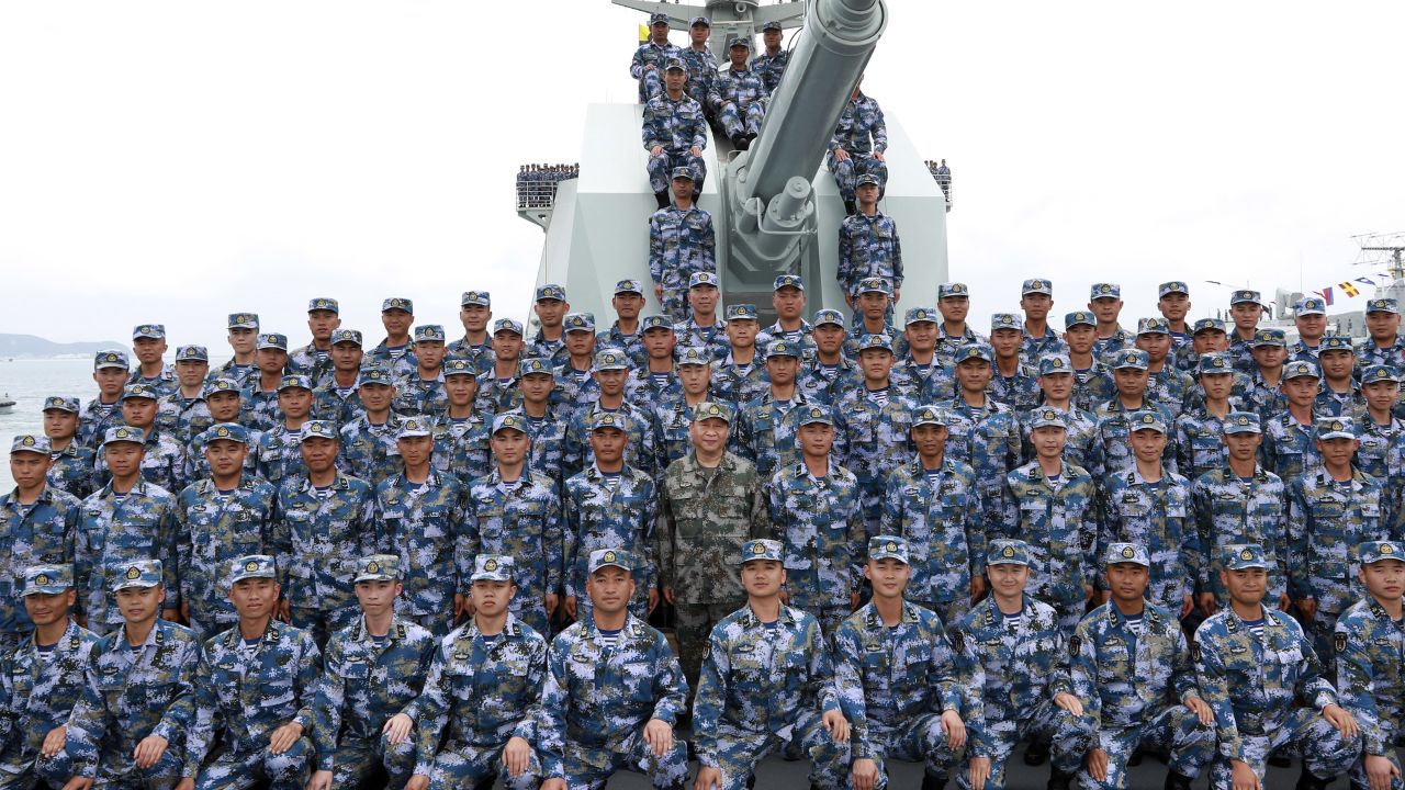 Chinese President Xi Jinping, center in green military uniform, poses with soldiers on a navy ship on April 12.