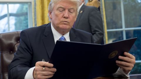 President Donald Trump reading the executive order withdrawing the US from the Trans-Pacific Partnership prior to signing it in the Oval Office on January 23, 2017.