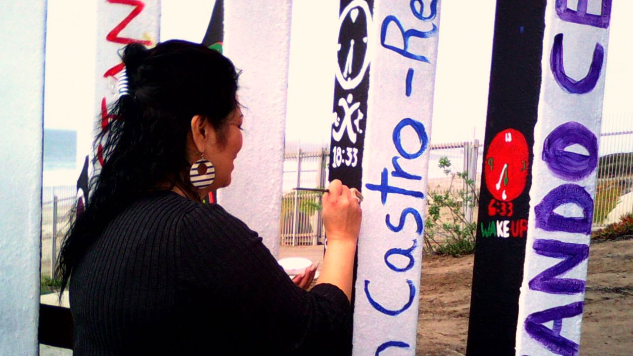 A volunteer paints names on the reverse side of the flag.