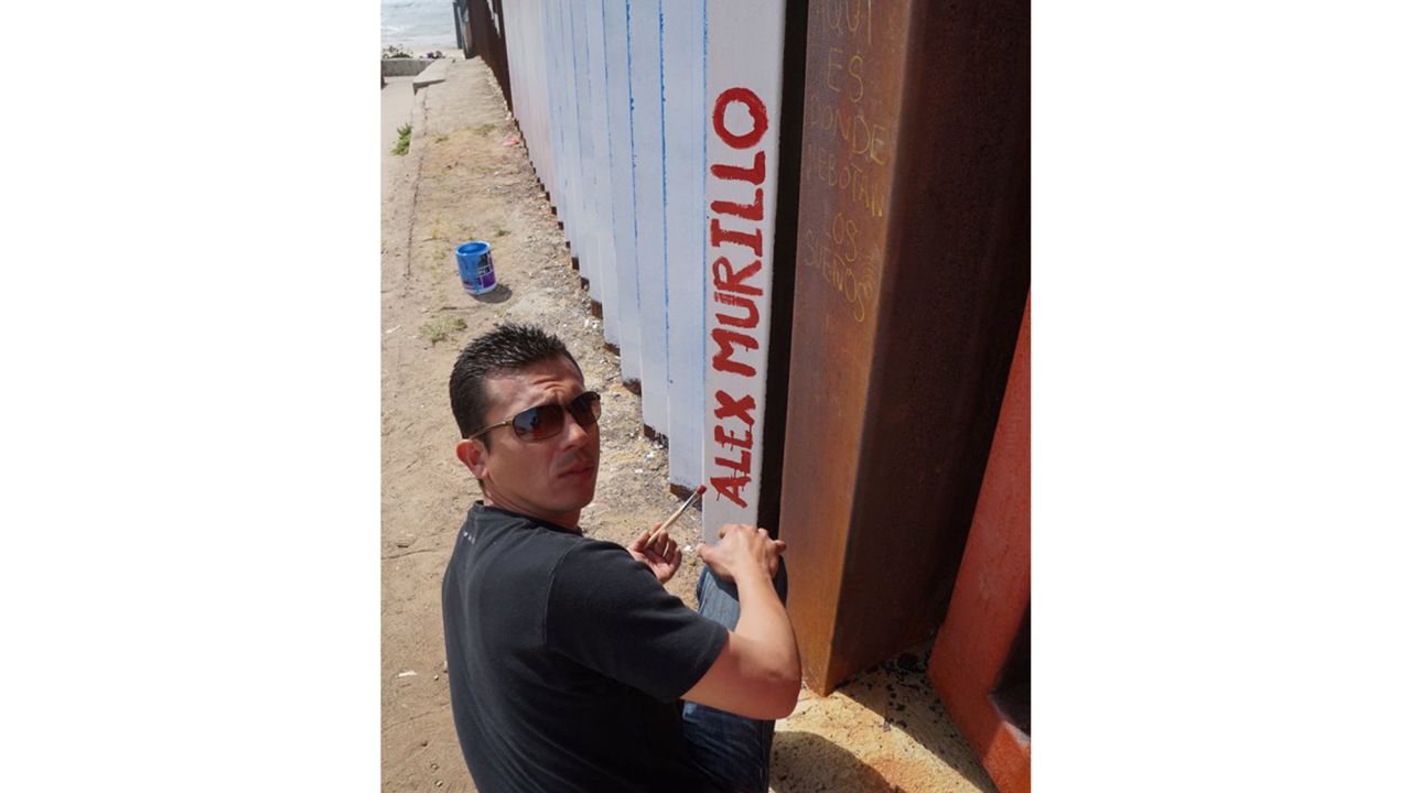 Alex Murillo, a deported US Navy veteran from Phoenix, paints his name on the upside down flag mural in Tijuana. Murillo was deported in 2012 after a drug conviction.