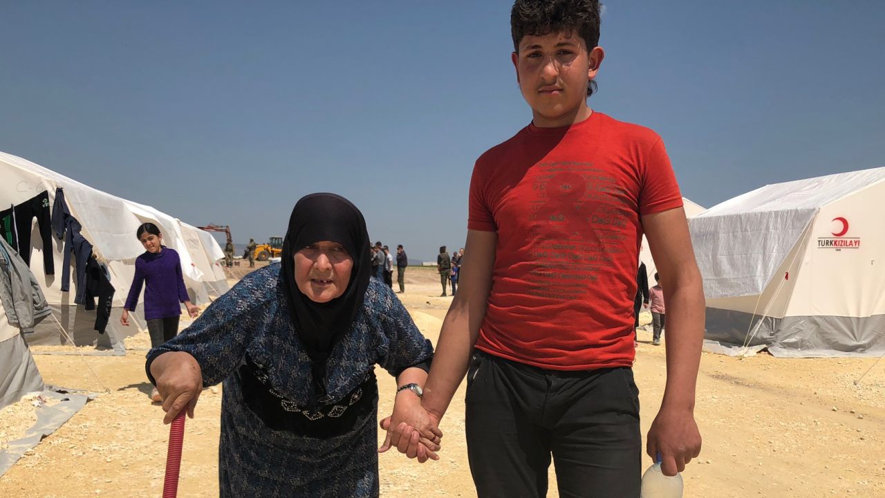 Fevziye, 68, is helped by a young man at a refugee camp in northern Syria.