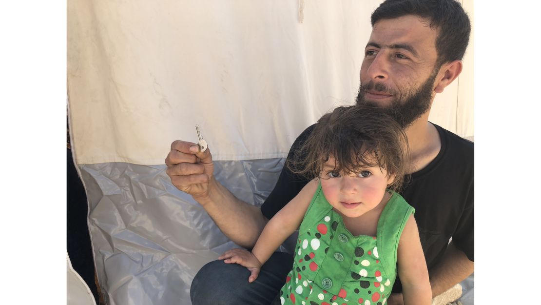 Walid Dervish, 23, pictured with his daughter, says he brought his Douma house keys with him to the refugee camp. "Maybe one day I can go back," he said. 
