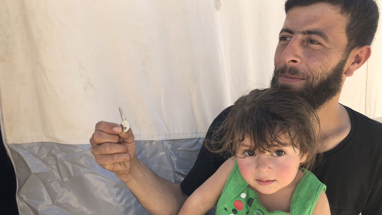 Walid Dervish, 23, pictured with his daughter, says he brought his Douma house keys with him to the refugee camp. "Maybe one day I can go back," he said.