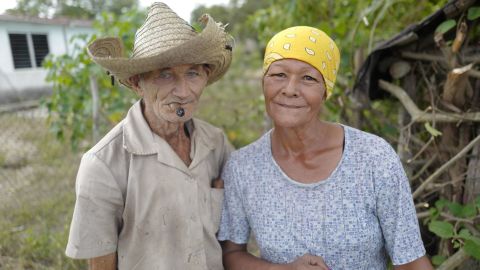 A couple in Céspedes, Cuba, pose in front of their home. After he took power in 1959, Fidel Castro promised to improve the lives of people living in Cuba's poverty-stricken countryside. He oversaw literacy and electrification campaigns and built hospitals for the rural poor. In recent decades, though, many Cubans living in the countryside have moved to cities, seeking better housing conditions and more economic opportunities.