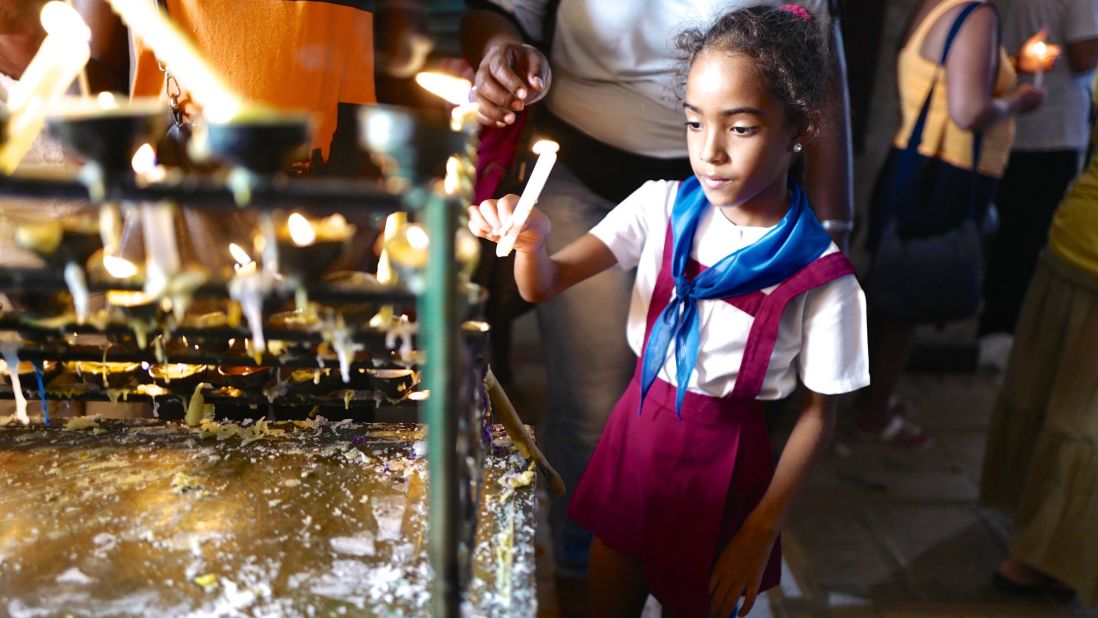 A young Cuban girl in her "pioneer" school uniform lights a candle at a Havana church days before the 2015 visit of Pope Francis to Cuba. Religion was all but banned following the Cuban revolution, and Catholics in particular faced government discrimination for openly practicing their faith. Over the last 20 years, the Cuban government has slowly eased restrictions on religion. In 2015, Raul Castro, a longtime atheist, said meeting the Pope made him consider returning to the Catholic church.