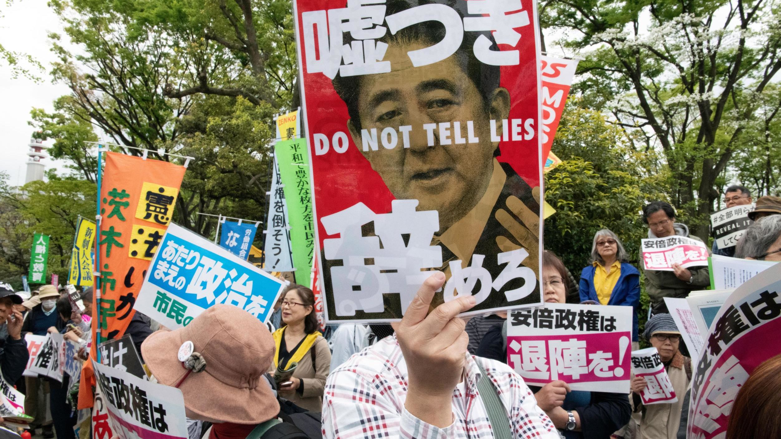 A protester holds a placard during a demonstration against Japan's Prime Minister Shinzo Abe on April 14, 2018.