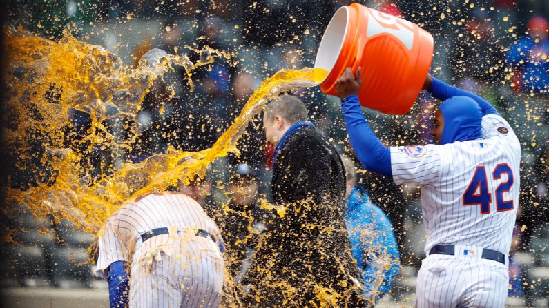 New York Mets left fielder Yoenis Cespedes, right, douses teammate Wilmer Flores after Flores hit a ninth-inning walk-off home run against the Milwaukee Brewers on Sunday, April 15, in New York.