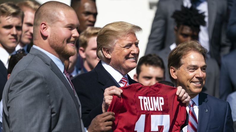US President Donald Trump holds up a jersey while University of Alabama football coach Nick Saban, right, looks on during an event honoring the 2017 NCAA football national champions, the Alabama Crimson Tide, on the South Lawn of the White House on Tuesday, April 10.