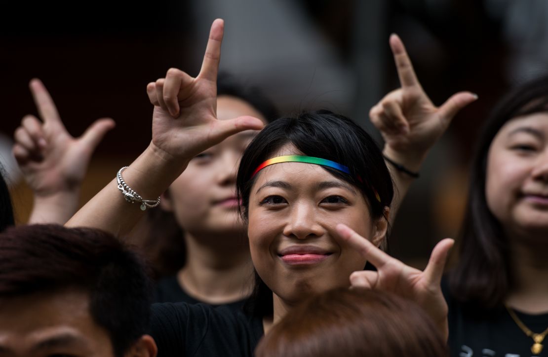 Runners in the 2016 Shanghai Pride Run make signs with their fingers while wearing rainbow shoelaces at the start of the race.