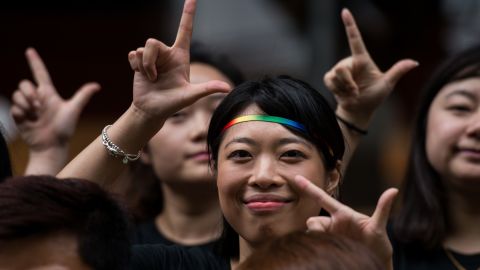 Runners of the Shanghai Pride Run make signs with their fingers while wearing rainbow shoelaces at the start of the race in Shanghai on June 18, 2016.