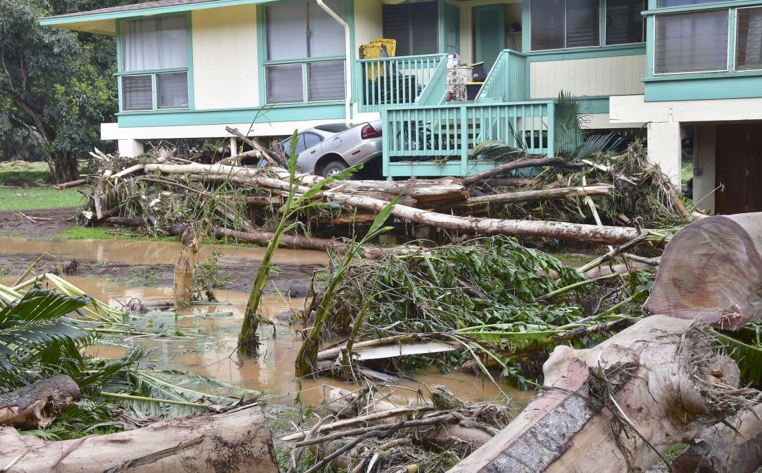 A car is wedged between a house and debris in Anahola, Hawaii, Sunday.